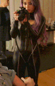 a woman with purple hair is taking a picture with her camera