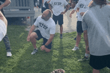 a man wearing a white shirt that says wingman on it kneels in the grass