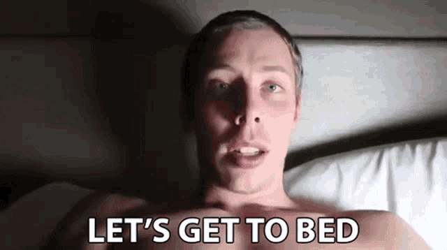 a shirtless man is laying in bed and saying let 's get to bed