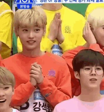 a group of young people are posing for a picture and one of them is wearing glasses and an orange shirt .