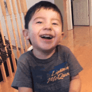 a young boy wearing a lightning mcqueen t-shirt is laughing