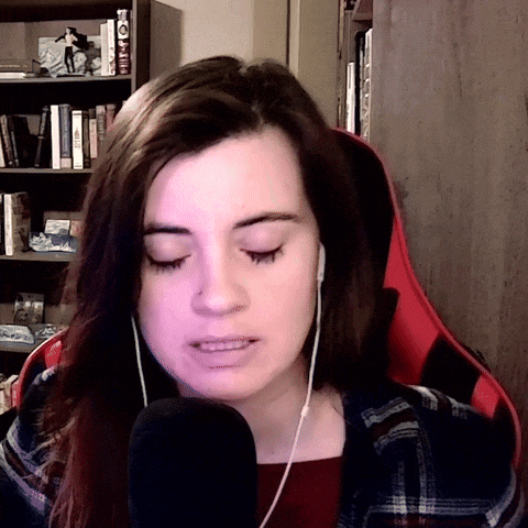 a woman wearing headphones and a plaid shirt looks at the camera
