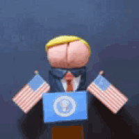 a puppet of donald trump is holding a podium with two american flags .