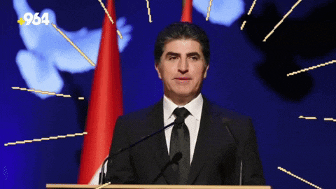 a man in a suit and tie is giving a speech at a podium with the number 964 in the corner