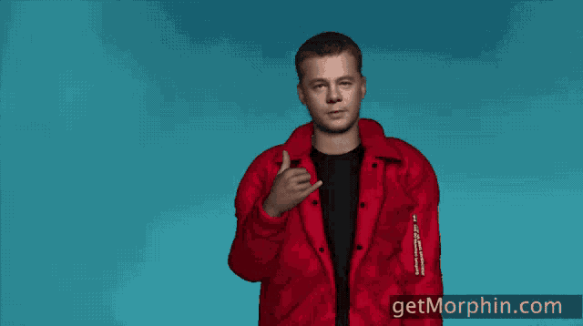 a man in a red jacket is making a call me sign