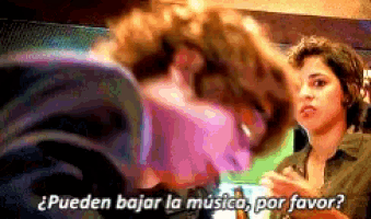 a woman is talking to another woman with the words " pueden bajar la musica por favor "