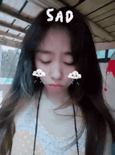 a girl with her eyes closed has the word sad on her head