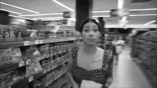 a woman in a polka dot dress is walking through a grocery store aisle