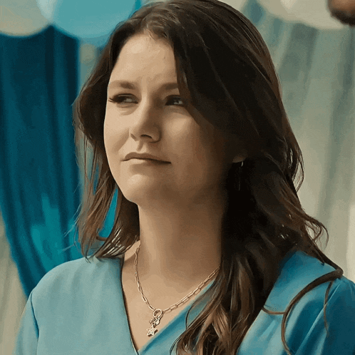 a woman wearing a blue shirt and a necklace with a star on it