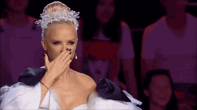 a woman in a white and black dress covering her mouth with her hand