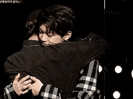 two men are hugging each other on a stage .