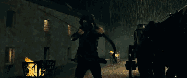 a man in a black suit is holding a sword in a dark room