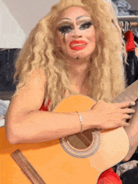 a drag queen is holding a guitar and making a face