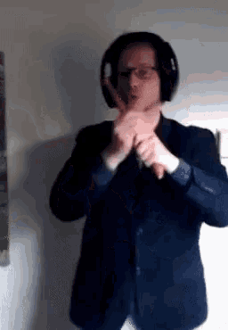 a man in a suit and headphones is making a gesture