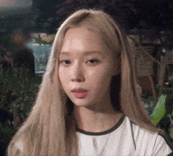 a woman with long blonde hair is wearing a white shirt and a necklace .
