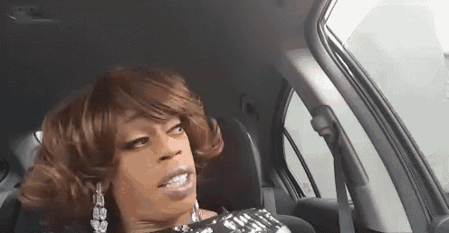 a drag queen is sitting in the driver 's seat of a car .
