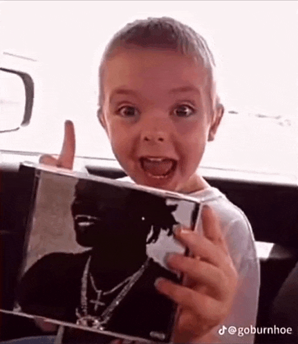a young boy is holding a picture of a man in a car .