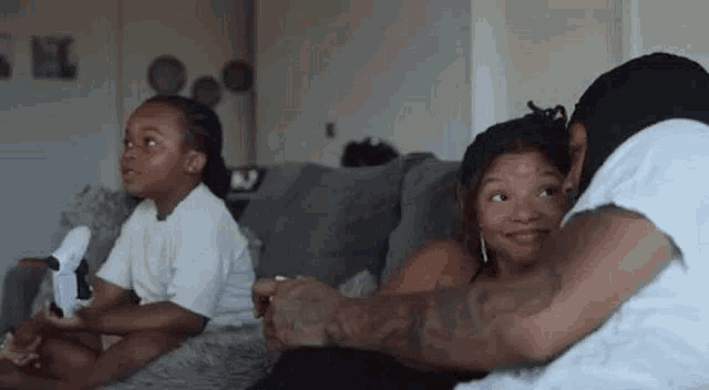 a man and a woman are sitting on a couch playing a video game with two children .