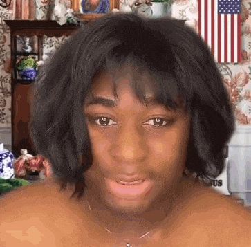 a woman wearing a wig and a necklace is making a funny face .