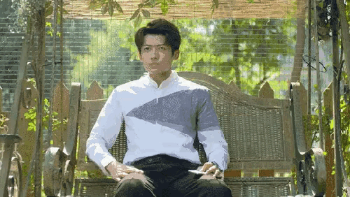 a man in a white shirt is sitting on a wicker swing .
