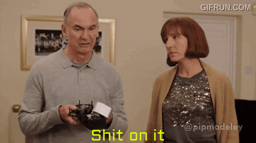a man and a woman are standing next to each other and the man is holding a camera and the woman is saying shit on it