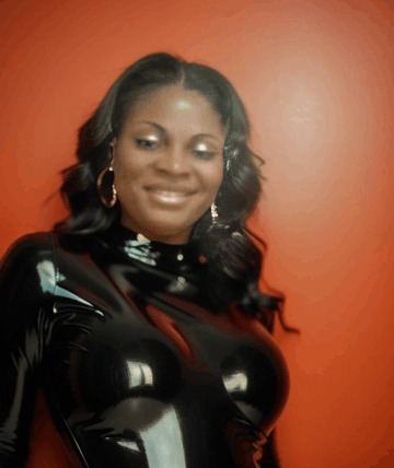 a woman in a black latex outfit is smiling and looking at the camera