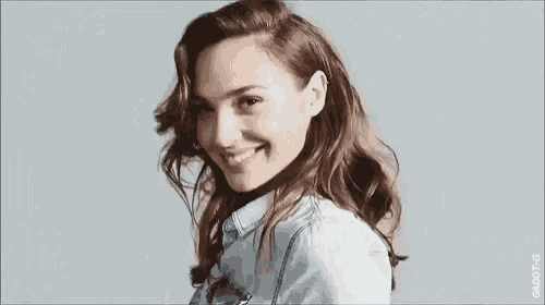 a close up of a woman wearing a denim shirt smiling .