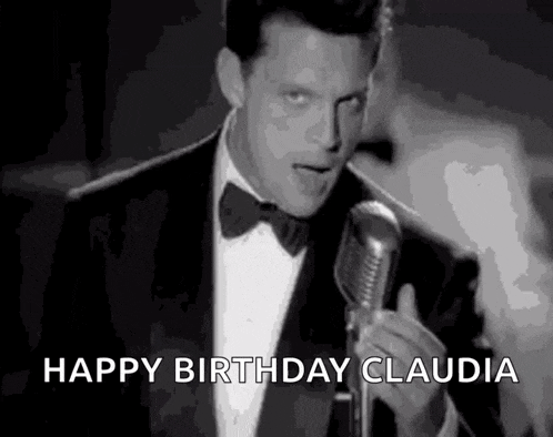 a man in a tuxedo is holding a microphone and singing into it .
