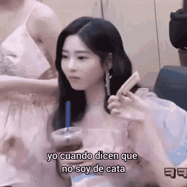 a woman in a pink dress is drinking from a plastic cup with a straw and holding a stick .