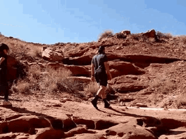 a man and woman are walking up a rocky hillside .