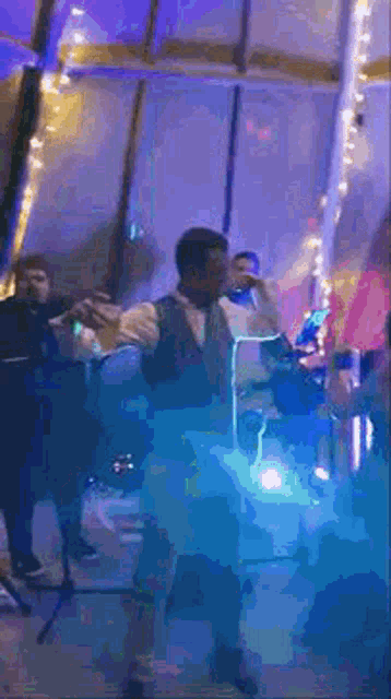 a man is singing into a microphone while standing in front of a crowd .