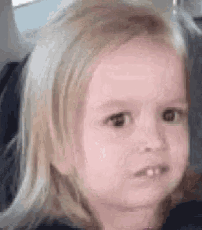 a little girl with blonde hair is making a funny face with her mouth open .
