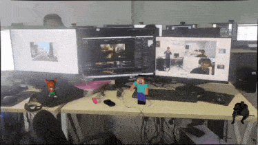 a man sits at a desk in front of three computer monitors one of which has a minecraft character on it