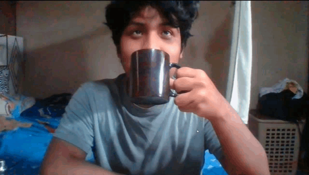 a young man is drinking from a coffee mug
