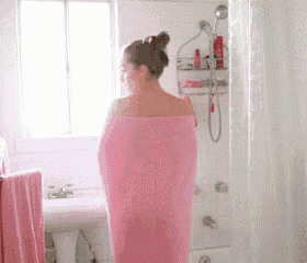 a woman is wrapped in a pink towel in the bathroom .