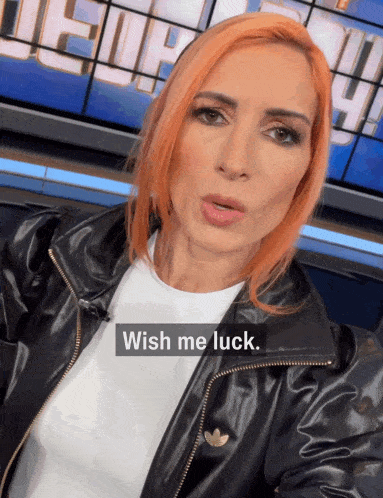 a woman with red hair is wearing a black leather jacket and says wish me luck