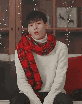 a man wearing a white sweater and a red scarf
