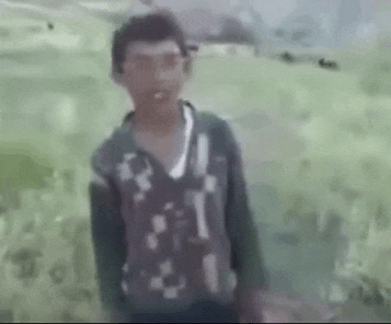 a young boy is standing in a field with a blurred background .