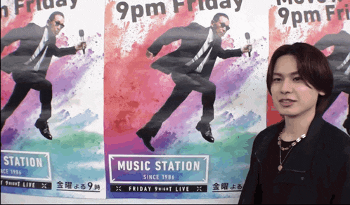 a man stands in front of three posters for music station