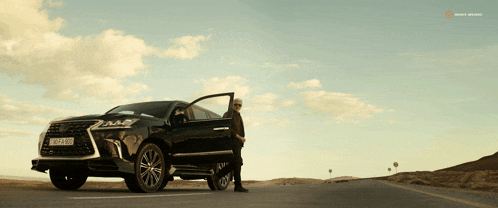 a man is standing next to a black lexus suv with a license plate that says lx - lx - 987