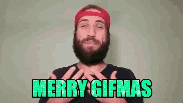 a man with a beard wearing a red hat and a black shirt says merry gifmas