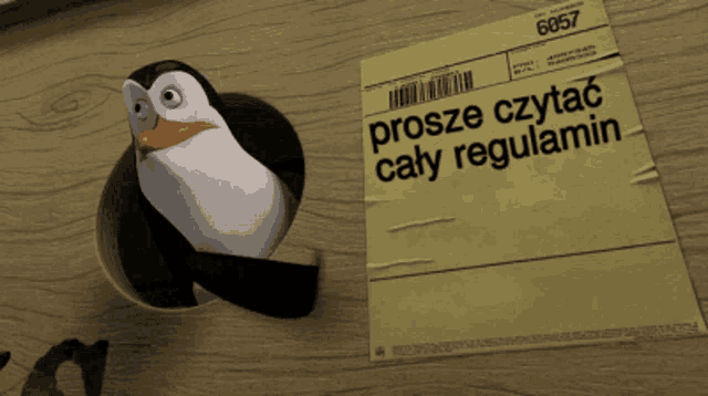 a penguin is sticking its head out of a hole next to a paper that says prosze czytac cały regulamin