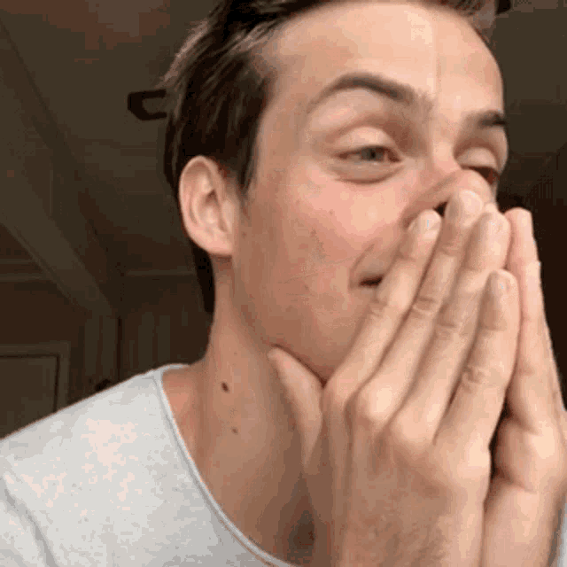 a man is covering his mouth with his hands and smiling .