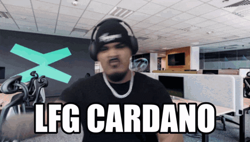 a man wearing headphones says lfg cardano in front of an office