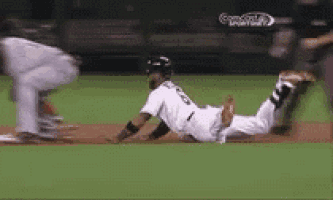 a baseball player is sliding into home plate while another player tries to tag him out .