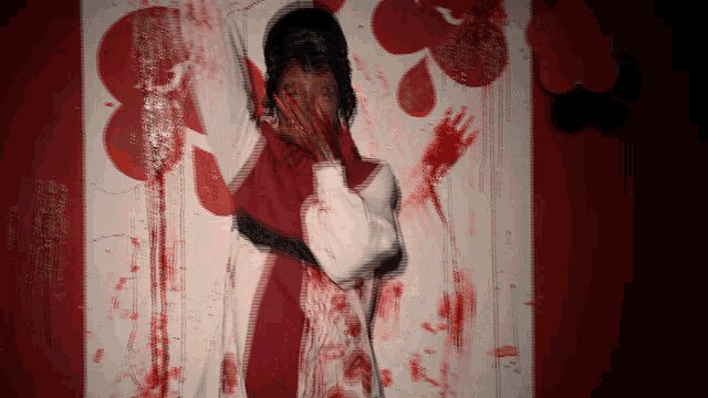 a person covering their face with their hands in front of a bloody canadian flag