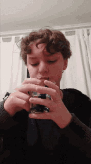 a young man is drinking from a shot glass with a straw