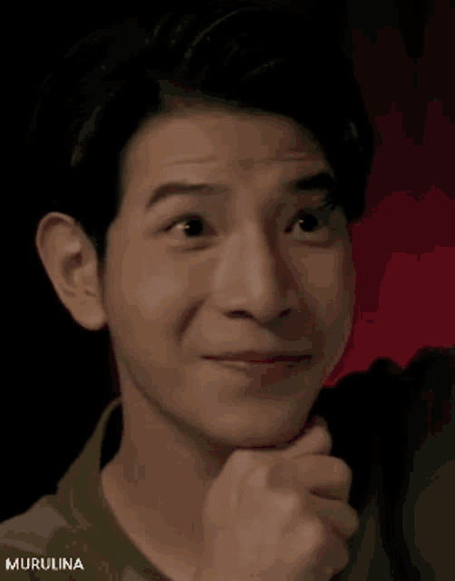 a close up of a young man 's face with his hand on his chin .
