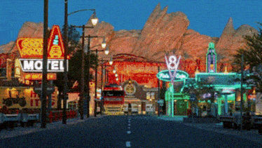 a motel sign is lit up at night in front of a mountain
