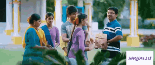 a group of people are standing in front of a building and a man is holding a book ..